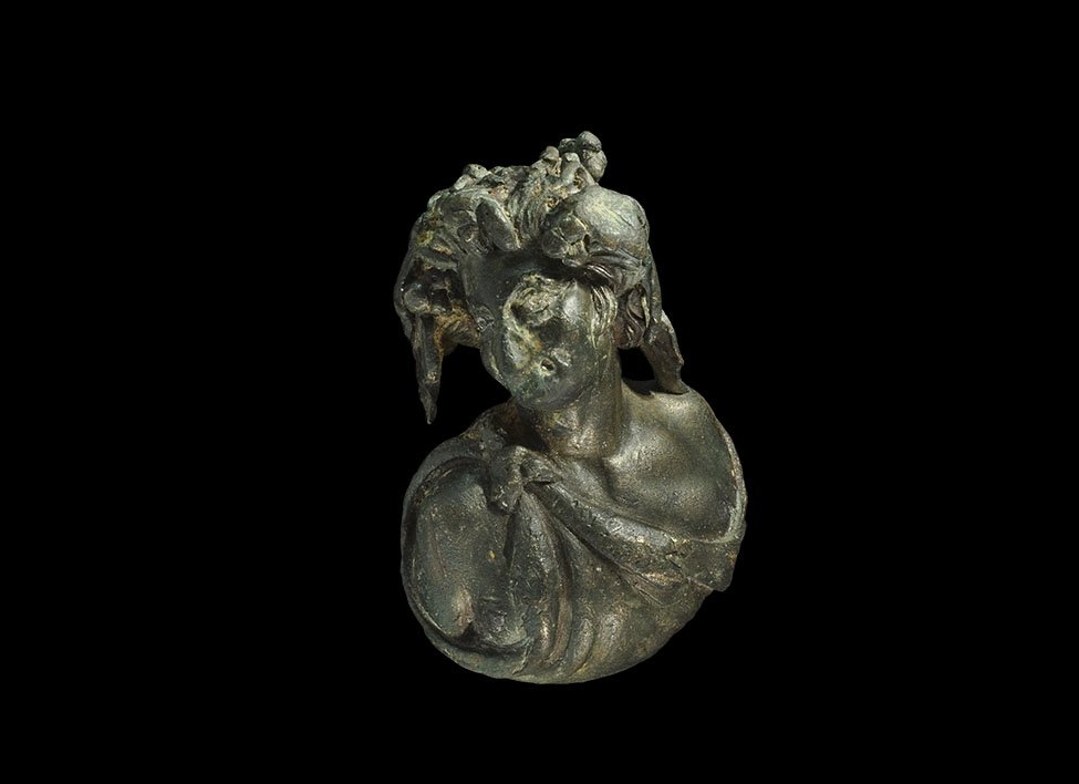 Roman Bronze Masked Dionysus Steelyard Weight: 2nd-3rd century AD. A cast bronze steelyard weight in the form of a male bust modelled in the round depicting the god Dionysus with a crown of vineleaves and berries, mask to the nose and mouth, chito