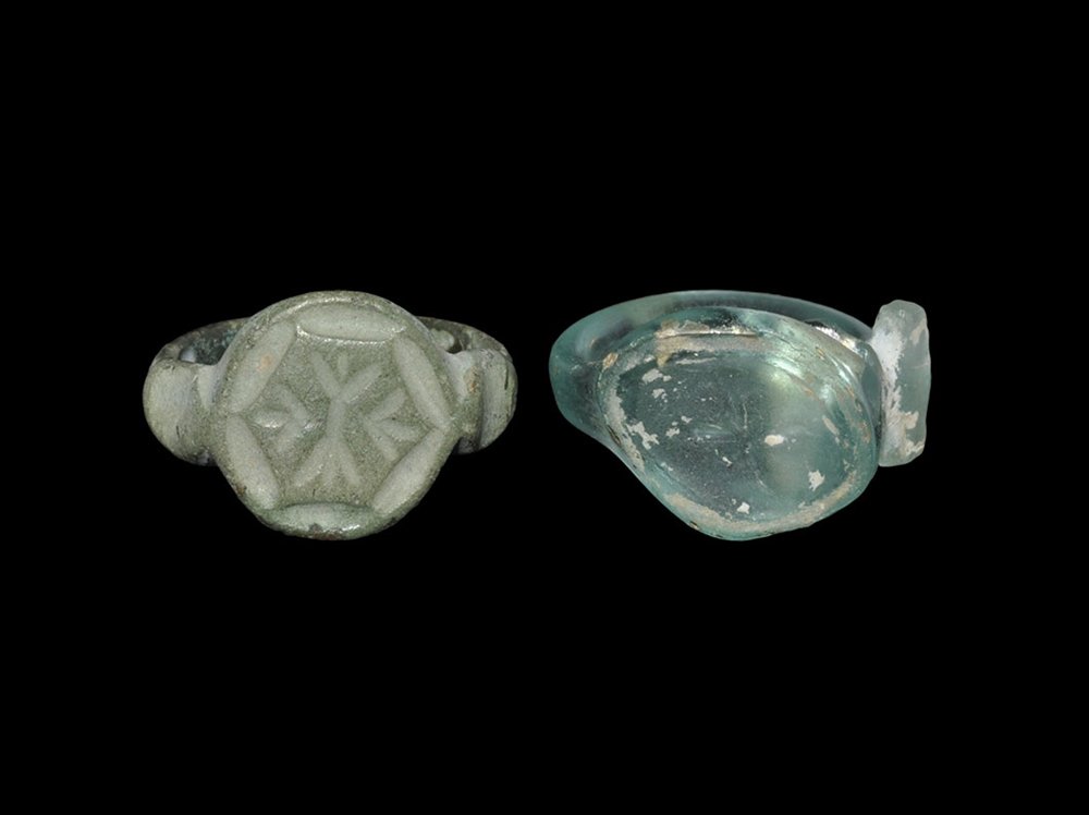 Byzantine Bronze and Glass Ring Group: 13th century AD and earlier. A mixed group of finger rings comprising: one in blue glass with round-section hoop, scaphoid bezel with intaglio saltire, plate to one shoulder; one bronze with D-section