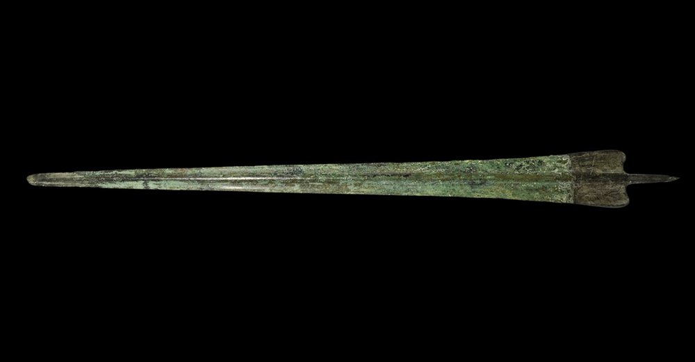 Greek Trojan Bronze Sword Blade: 12th-10th century BC. A cast Bronze Age rapier with narrow triangular blade, thick rounded midrib, rounded tip, scooped shoulders with lateral flanges, round-section tang with flattened finial. Cf. Br