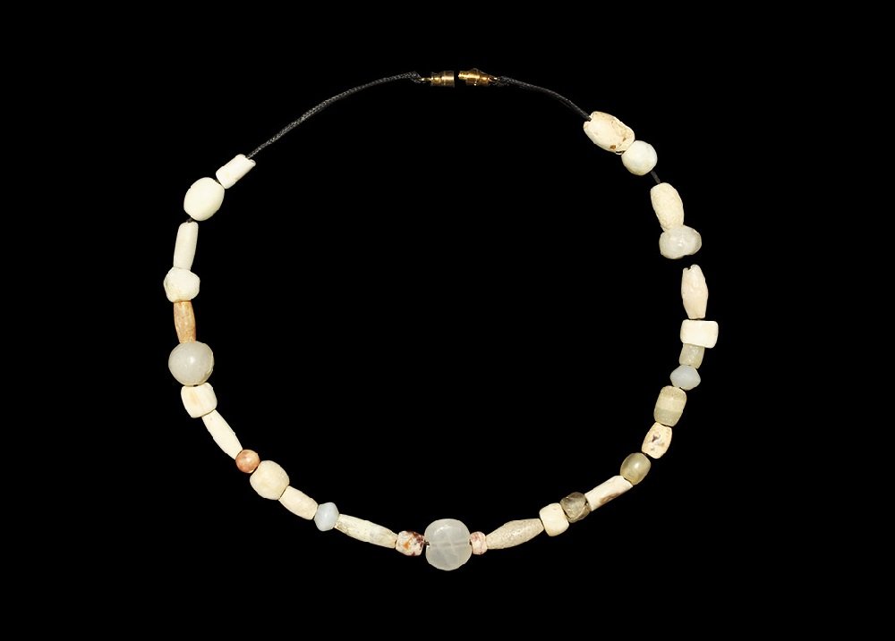 Near Eastern Syrian Stone Bead Necklace: 1st millennium BC. A restrung necklace of ancient white stone beads, mainly barrel, cylindrical and oblate shapes, featuring a central rounded tabular disc bead. 31 grams, 44 cm (17 1/4"). Ex Steinber