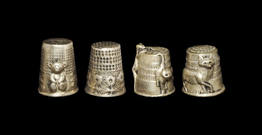 Vintage White Metal Thimble Group: 20th century AD. A mixed group of cast novelty thimbles comprising: one with a row of flowers to the lower edge; one similar, teddy bear modelled in the half-round; one with two foxes; one with three