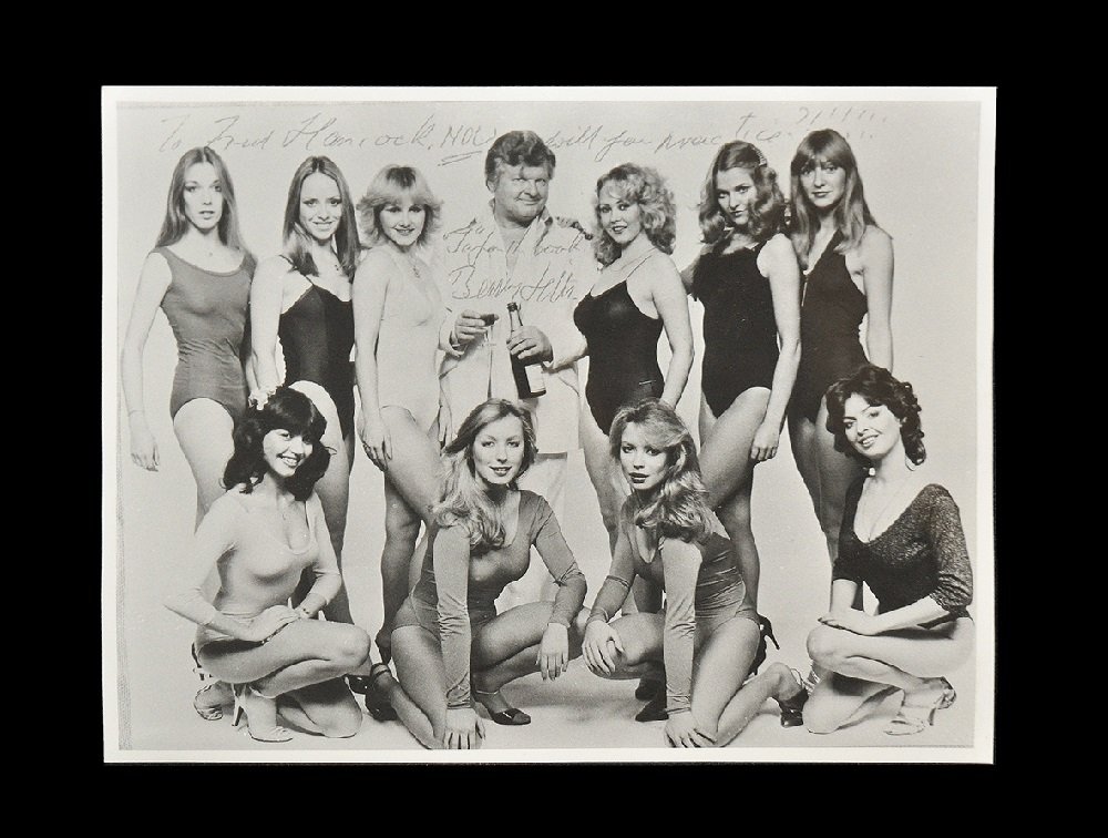 Memorabilia Benny Hill Signed Photograph: 1980s. A black and photographic studio print showing Benny Hill (1924-1992) with ten of his 'Hill's Angels' and autographed with 'To Fred Hancock NOW will you practice?!!!!!!' and 'Ta for the book' de