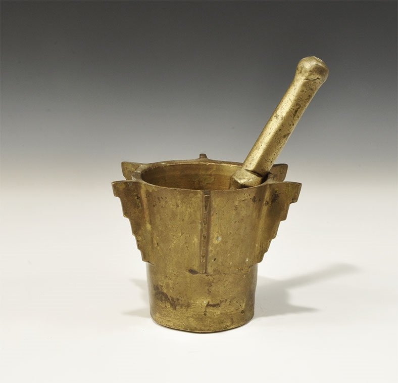 Islamic Brass Pestle & Mortar: 19th century AD or later. A cast pestle with facetted bulb to the shaft, domed ends; mortar of funicular profile with six radiating stepped flanges. 2.3 kg, pestle: 22 cm (8 3/4"). Ex Steinberg collec