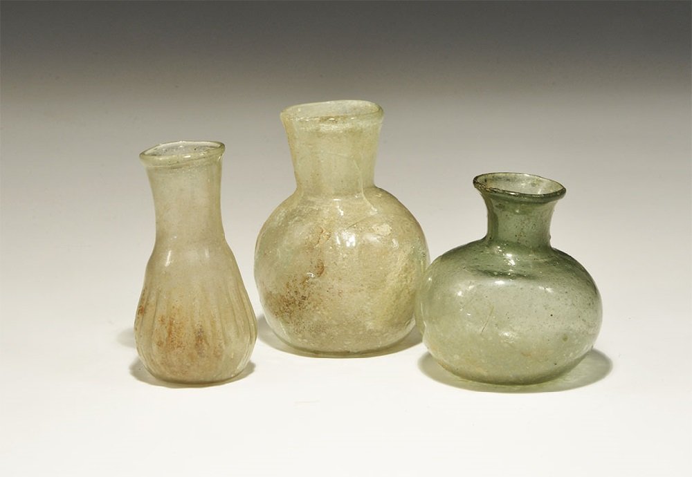 Roman Glass Miniature Bottle Group: 2nd-3rd century AD. A mixed group of pale green vessels comprising: a mould-blown jar with dimple base, funicular neck; a squat jar with broad neck, rolled rim; a flask with pinched vertical ribbing. 