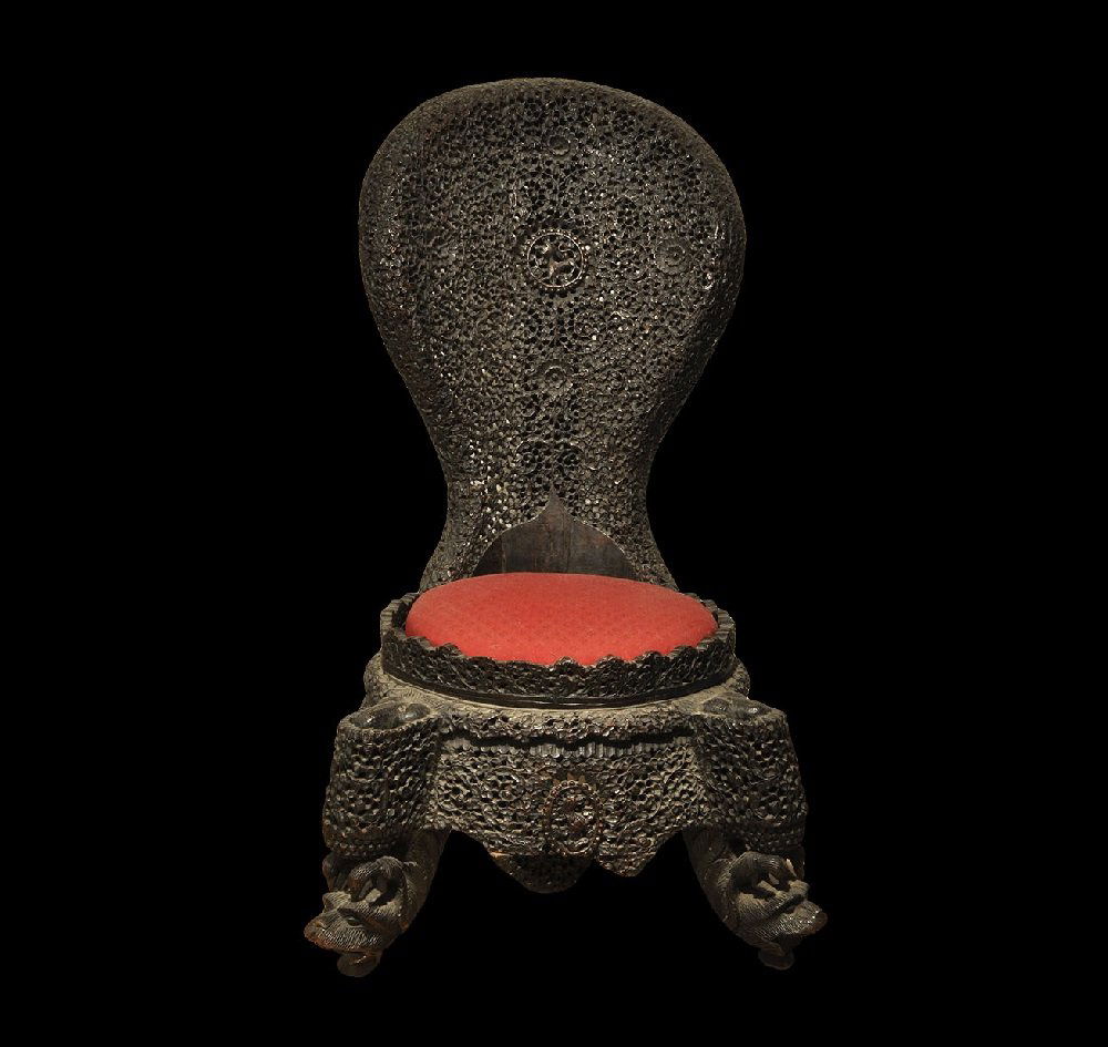 Far Eastern Burmese Carved Wooden Chair: Late 19th-early 20th century AD. A carved chair with low seat and high back, the back and base pierced with floral and tendril designs; the two rear legs with lion-heads at the top, the front legs wit