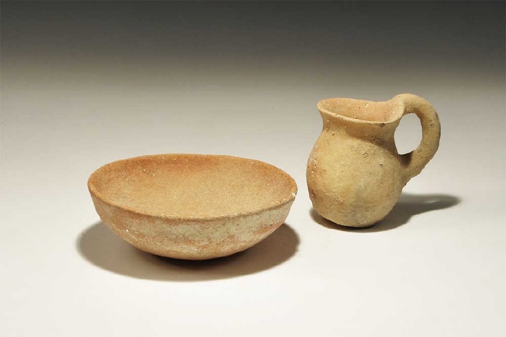 Roman Ceramic Redware Juglet & Bowl Group: 2nd-4th century AD. A mixed group of terracotta vessels comprising: a hemispherical bowl with slight carination below the rim; a round-bottomed juglet with flared rim and round-section handle to the r