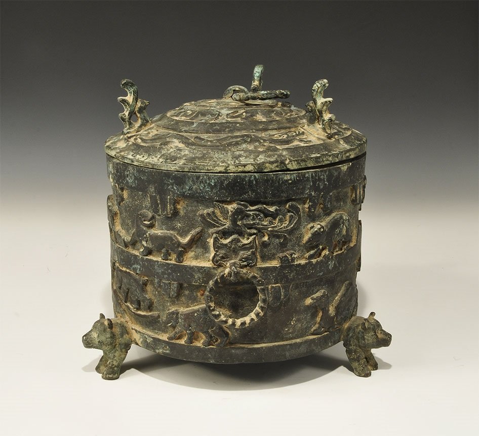 Chinese Style Bronze Lidded Vessel: An undated archaistic drum-shaped vessel with three legs, each formed as a bear; two free-running loop handles in animal-mask escutcheons; two friezes of reserved advancing animals to the outer wall o