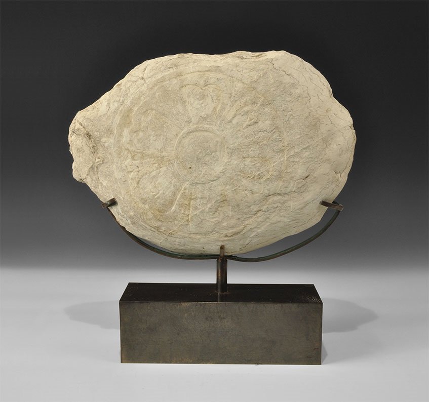 Near Eastern Limestone Panel with Kufic Inscription: 10th century AD An elliptical panel of limestone carved with a sexfoil with Kufic text within each panels and the central roundel; mounted on a custom-made stand 11.7 kg, 45 cm including stand (17 1/2