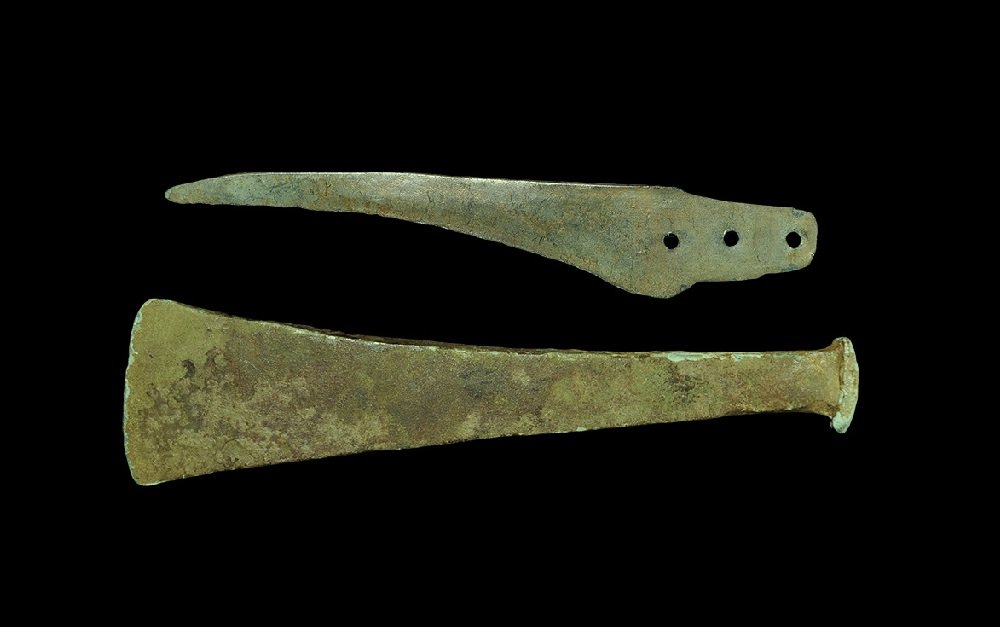 Bronze Age Blade and Chisel Group: 1st millennium BC A mixed group of bronze tools comprising: a flat-section chisel with broad convex-edged and clubbed butt; a slender single-edged blade, slightly curved, with tang pierced in three pl