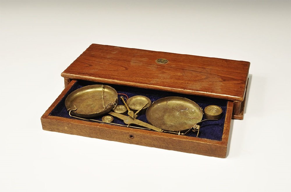 Vintage Wood-Cased Brass Balance Scales & Weights Set: 20th century AD. A miniature scale with balance arm and pointer, two dished pans, four weights (10, 20, 50 and 100 grams), supporting leg with screw thread to attach to the upper face of the box formi
