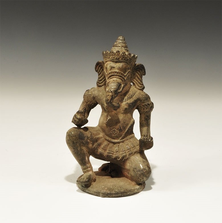 Cambodian Style Bronze Ganesh Figurine: An undated archaistic cast figurine of Ganesh, crown and kilted, kneeling on a discoid base. 1.3 kg, 17.5 cm (7"). From an old London collection, formed in the 1980s.
