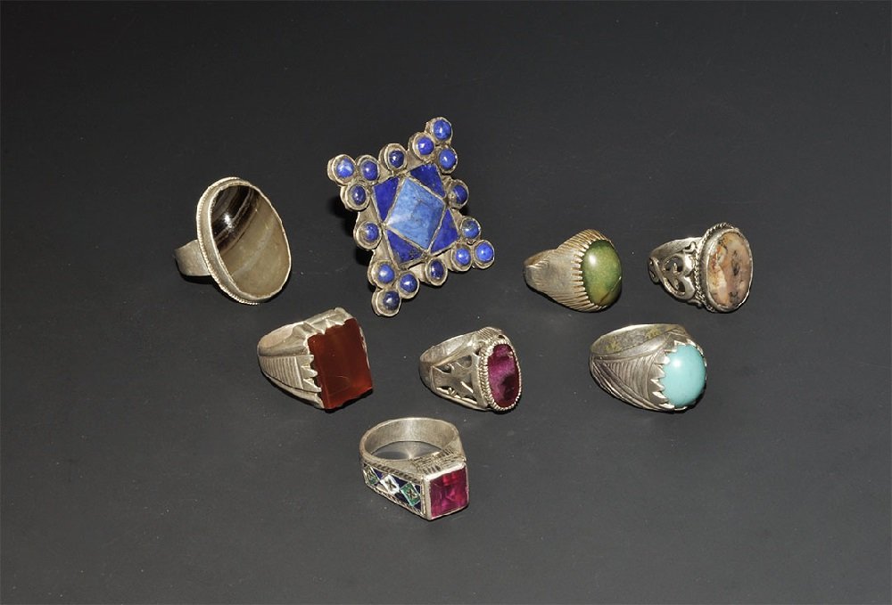 Central Asian Silver Coloured Metal Ring Group: 20th century AD. A mixed group of eight finger rings with cabochon and cloison inserts of natural and imitation stones. 94 grams total, 29-55mm (1 - 2"). From a large London collection; formed between