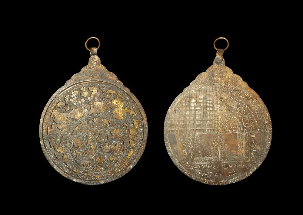 Islamic Style Bronze Astrolabe: An undated archaistic cast astrolabe with spigot and rotating openwork panel, D-shaped block with strap and suspension loop; incised quadrants and numerals to the reverse; inset with blue cabochons. 3