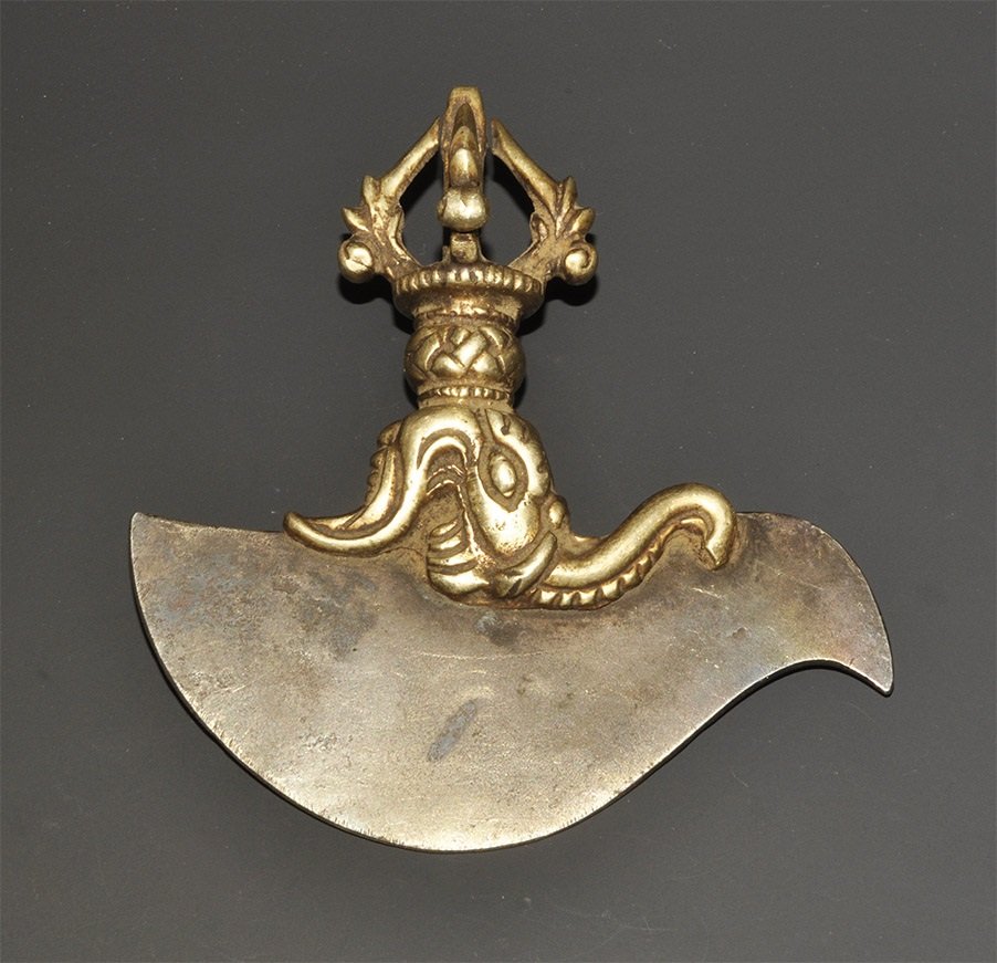 Chinese Tibetan Bronze Axe Pendant: 20th century AD. An iron swept trigug blade with cast bronze fitting to the upper edge of an elephant's head in profile surmounted by four arched foliate bars forming a vajra. 151 grams, 11.5cm (4 1/2