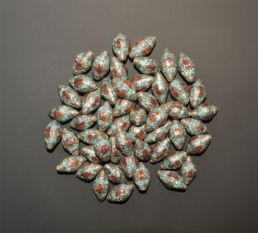 Ethnographic Biconical Bead Group: 20th century AD. A group of silver-coloured metal biconical beads with inset turquoise, carnelian and lapis lazuli chips; Pakistani workmanship. 418 grams total, 26-27mm (1"). Property of a London gen