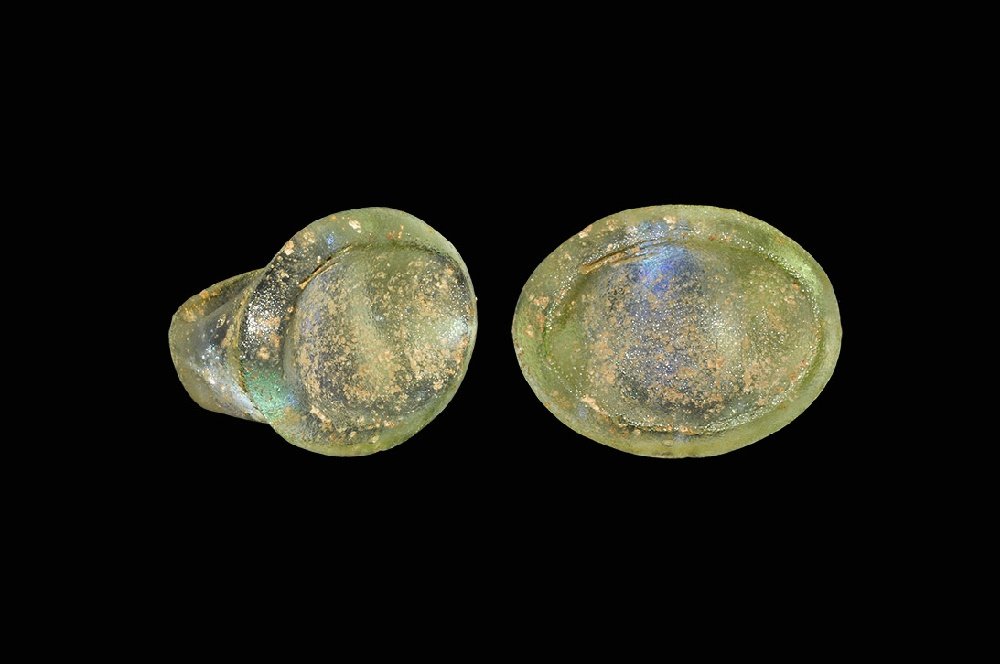 Roman Glass Finger Ring: 1st-2nd century AD. A pale green glass ring with broad D-section hoop, elliptical bezel with chamfered outer edge, shallow indented centre. 7.68 grams, 29mm overall, 13.79mm internal diameter (approxi