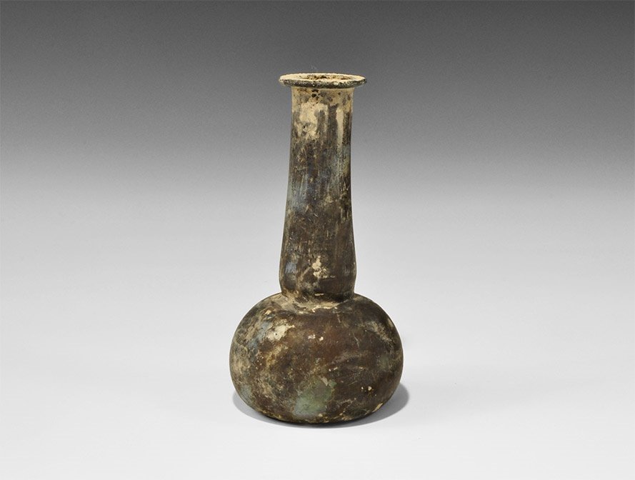 Roman Aubergine Glass Flask: 2nd-3rd century AD. A tall aubergine-coloured flask with bulbous base, folded flange rim to the mouth. 97 grams, 13.5cm (5 1/4"). Property of a retired sculptor; from a collection formed in the 1980s.