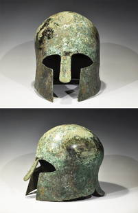 Greek Bronze Corinthian Helmet: Archaic Period, Late 7th century BC. A greek bronze helmet hammered from a single heavy sheet, of domed form, with a flaring neck-guard, elongated almond-shaped eye holes, and a protruding nose-guard