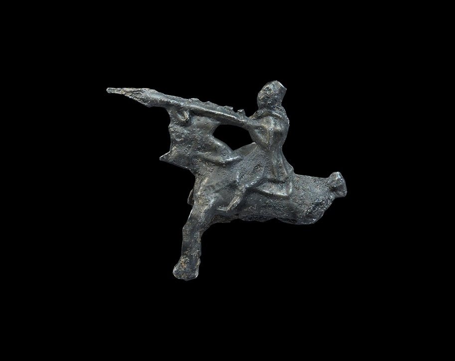 Medieval Pewter Jousting Knight Secular Figurine: 13th-14th century AD. A cast figurine of a mounted horseman in a tilting helm, his lance couched under his right arm, left side covered by a shield with raised cross design; the horse with chamfron, r