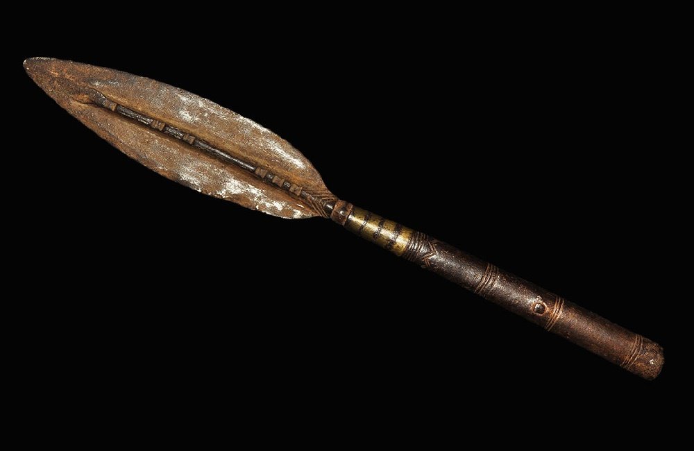Indian Brass-Inlaid Iron Spearhead: 19th century AD. A leaf-shaped blade with median rib and tubular split socket; the rib with transverse notches, the neck with four brass-inlaid rings, the socket with circumferential geometric bands; 