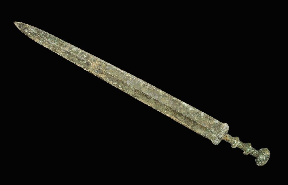 Chinese Bronze Epigraphic Sword: An undated archaistic cast Han Dynasty style sword with gently tapering blade, lozenge-section guard, columnar grip with two collars and discoid pommel; incised characters to one face. 814 grams, 55.5