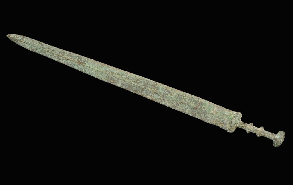 Chinese Bronze Epigraphic Sword: An undated archaistic cast Han Dynasty style sword with gently tapering blade, lozenge-section guard, columnar grip with two collars and discoid pommel; incised characters to one face. 821 grams, 65cm