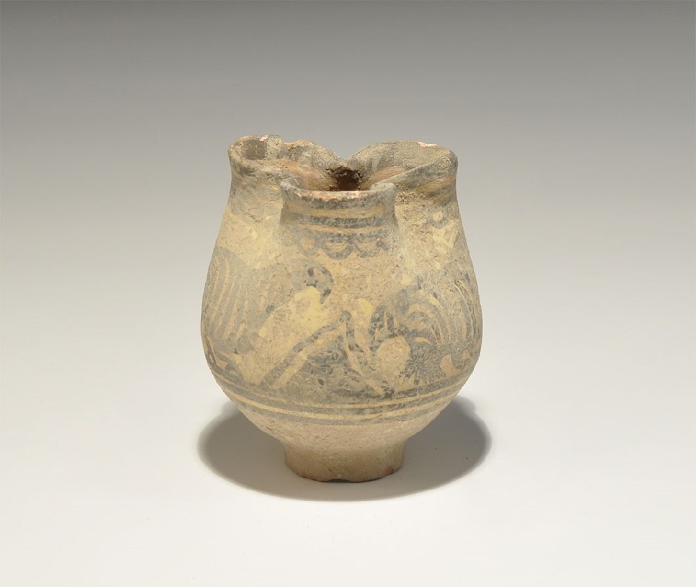Indus Valley Painted Ceramic Trefoil-Mouthed Cup: 3300-1300 BC. A delicate terracotta vessel with discoid base. bulbous body and pinched trefoil mouth; painted frieze of three birds within concentric borders. 98 grams, 75mm (3"). Ex Hiller collection