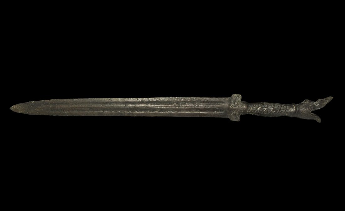 Chinese Style Bronze Sword with Dragon Pommel: . An undated archaistic Han Dynasty style sword with parallel-sided blade, balustered grip and tubular pommel formed as a serpent with open mouth; two columns of text and meander motifs to each face o
