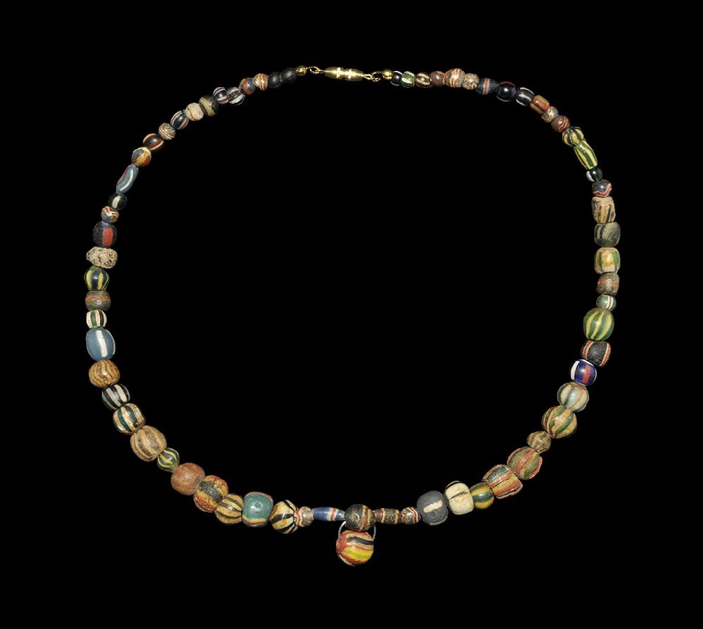 Egyptian Banded Mosaic Glass Designer Necklace: Mainly Ptolemaic Period, 332-30 BC. A restrung necklace of of early glass beads from Alexandria, Egypt, including some ancient islamic drawn striped beads in irregular rounded shapes, with a larger on