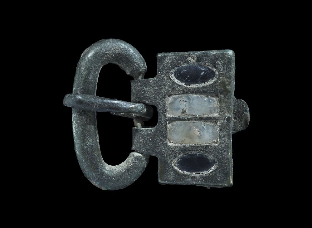 Merovingian Frankish Bronze Buckle with Gemstone: 5th-6th century AD. A buckle, plate and tongue of Merovingian Frankish style inset with two pairs of gemstones; the loop formed as an elliptical round-section bar narrowing on the rear edge to accommo