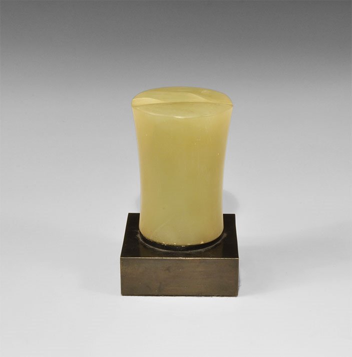 Near Eastern Bactrian Green Alabaster Idol: 3rd millennium BC. A carved tapering columnar idol with transverse slot to each flat face; mounted on a custom-made stand. 836 grams, 12cm including stand (4 3/4"). Ex Rabi Gallery, Mayfair, London, U