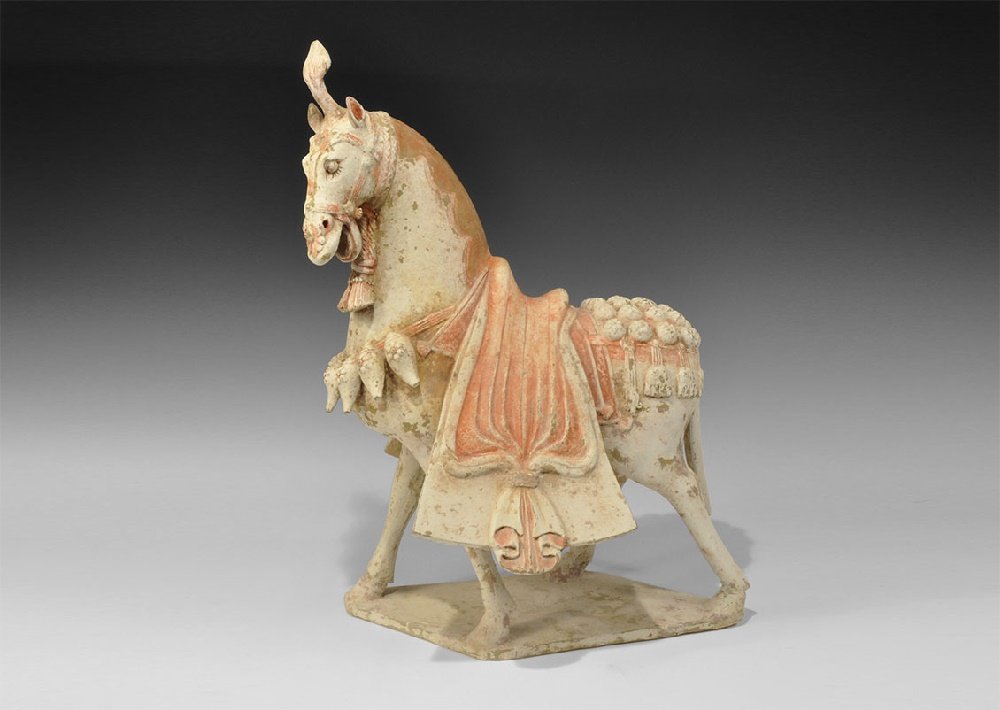 Chinese Ceramic Large Painted Horse: Northen Wei Dynasty, 386-534 AD. A standing horse figurine on a rhomboid base with integral flared saddle and bridle, plume to the forehead and bells to the chest and rump; coral pigment to the saddle