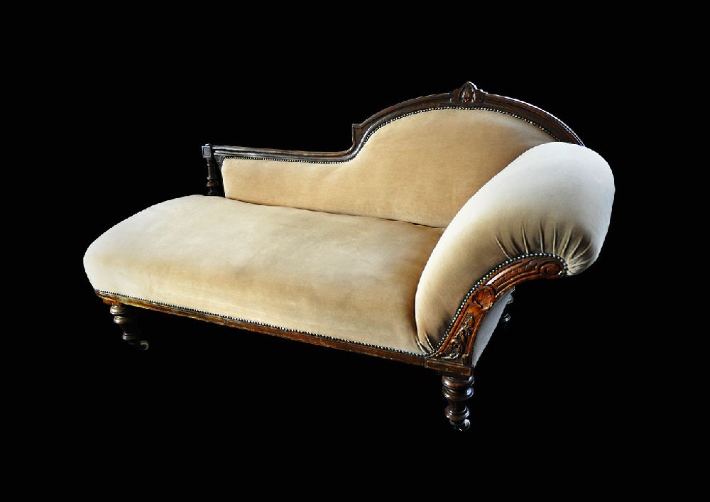 Antique Victorian Chaise Longue: 19th century AD. A traditional chaise longue settee with arm to right side, the stained and varnished timber frame with carved detail and supported off four turned legs, each with brass and ceramic ca