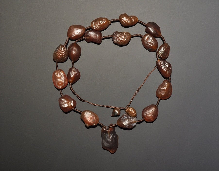 Western Asiatic Large Glass Bead Necklace: 20th century AD. A designer necklace of irregular carnelian nugget beads on cord with a central pendant. 155 grams, 82cm (32 1/4"). Ex South London collection; acquired in the late 1990s. TimeLine Auc