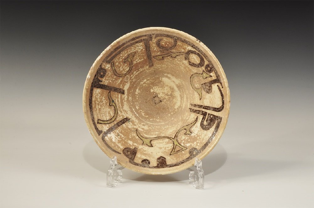 Islamic Style Glazed Ceramic Bowl: A broad funicular undated archaistic bowl with basal ring, white-glazed with band of Kufic text to the inner face, green foliage and central pellet. 619 grams, 25.5cm (10"). From a central London coll
