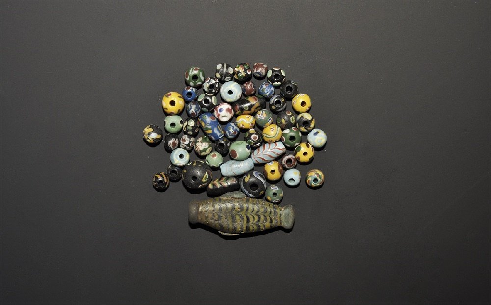 Islamic Safavid Style Glass Bead Collection: 20th century AD. A mixed group comprising: a fish-shaped bead; five tapering tubular; two large globular; forty-four globular. 46 grams total, 7-47mm (1/4 - 1 3/4"). Acquired on the London art market 