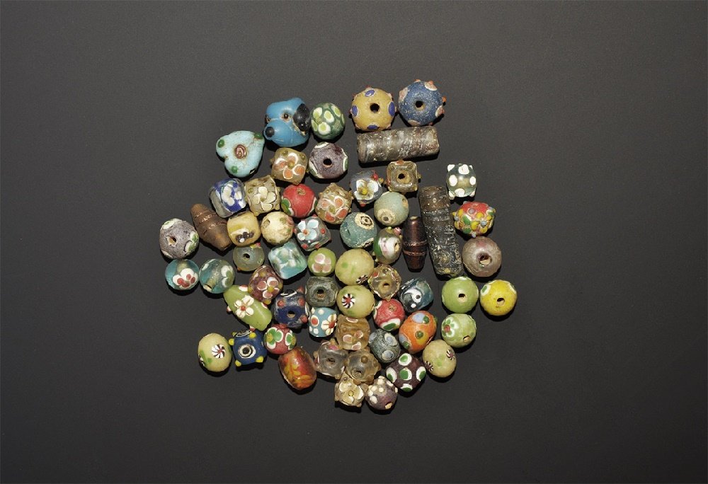 Islamic Safavid Style Glass Bead Collection: 20th century AD. A mixed group of glass beads comprising: two brown tubular; two biconical; nine globular with applied knops; five cuboid; thirteen cuboid with applied knops; twenty two globular; five