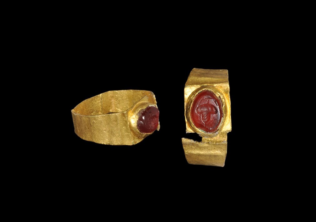 Roman Gold and Garnet Ring with Acorn Intaglio: 3rd century AD. A flat-section hoop with flat plaque, inset garnet cloison with intaglio acorn motif. 1.70 grams, 17mm overall, 13.54mm internal diameter (approximate size British E, USA 2 1/4, Europe