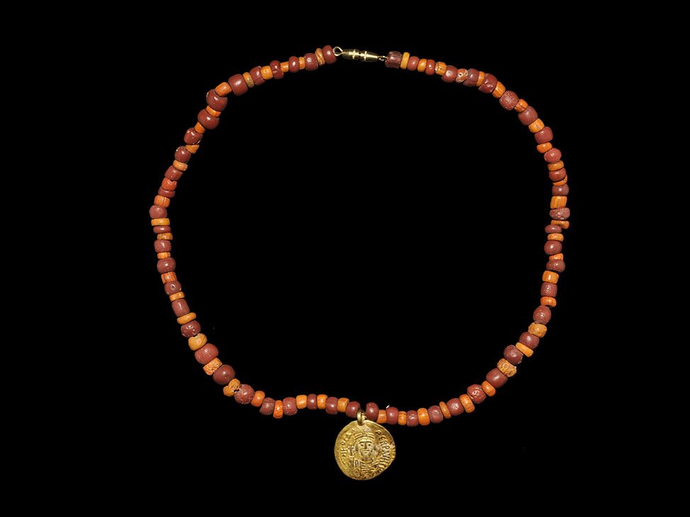 Byzantine Gold Coin Pendant Necklace: Coin dated 602-610 AD. A designer necklace of rounded and cylinder-shaped coral beads, featuring a gold Solidus coin pendant of Emperor Phocas; modern clasp. 24 grams, 38cm (15"). Property of a North 