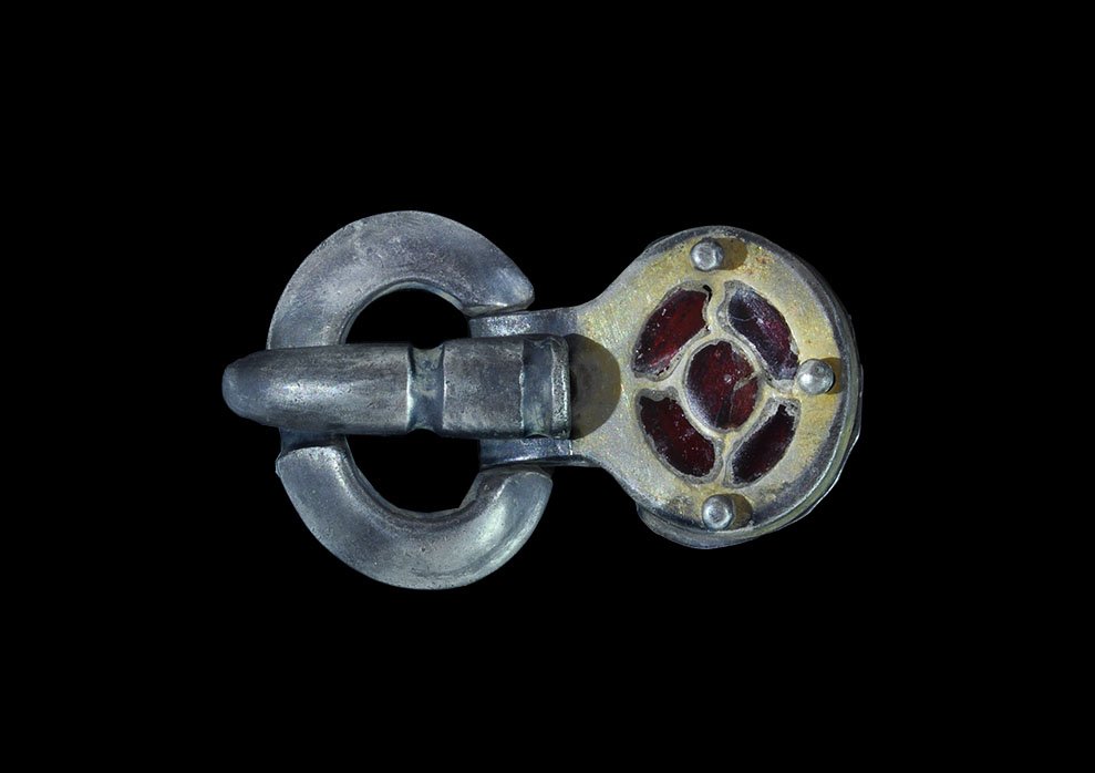 Gothic Silver-Gilt Buckle with Garnets: 6th century AD. A three-part buckle set comprising: a D-section loop with couch to the forward edge; a slender D-section tongue curved over the forward edge of the loop; a parcel-gilt discoid plate wi
