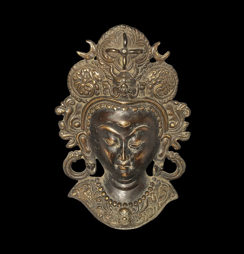 Indian Bronze Tara Bust Applique: Nepal, 19th-early 20th century AD. Cast bronze bust applique of the goddess Tara with third eye and elaborate headdress in the form of three large rosettes with foliate scroll pattern and a kirittimuk