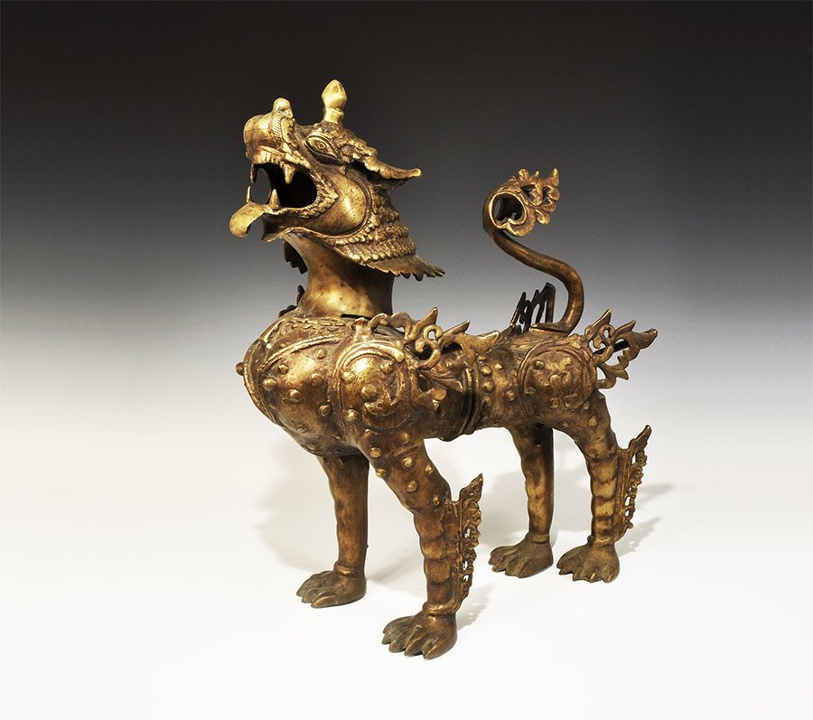 Chinese Nepalese Bronze Temple Lion: Nepal, 19th-early 20th century AD. A large cast bronze figure of a temple lion with open mouth and lolling tongue and with flame like fur on the shoulders and legs; tail ends in a floral motif. 17.9 k