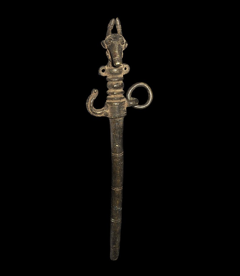 Indian Bronze Bull Headed Animal Goad: India. 19th-early 20th century AD. Cast bronze goad with three double incised lines on the shaft; above is an upward curving hook and suspension ring to the other side; above is a decorative finial in