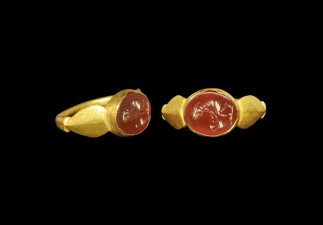 Roman Gold Ring with Carnelian Intaglio: 3rd century AD. A rounded-section hoop with flat leaf-shaped shoulders, discoid cell to the bezel with inset carnelian intaglio design of a woman picking up an amphora. Cf. Ruseva-Slokoska, L. Roman J