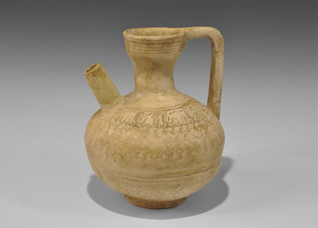 Islamic Terracotta Flagon with Spout: 12th-14th century AD. A vessel comprising a bulbous jug with funicular neck, strap handle and spout; bands of low-relief decoration. Cf. Lane, A. Early Islamic Pottery, London, 1958, pl.43. 488 grams,