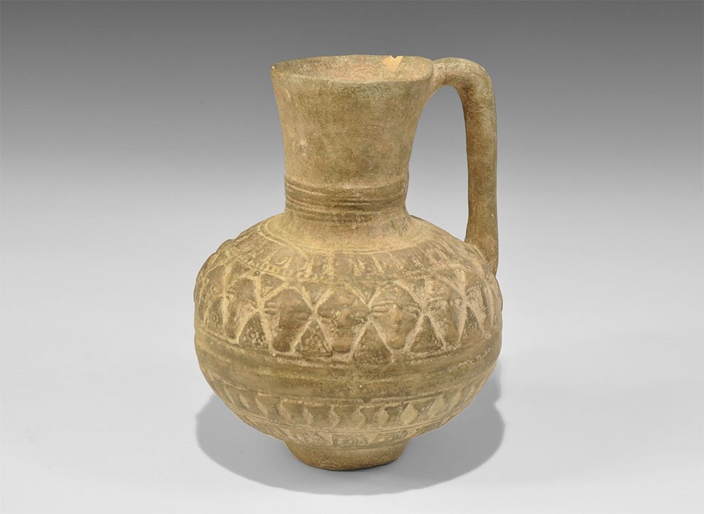 Islamic Terracotta Flagon with Faces: 12th-14th century AD. A vessel comprising a bulbous jug with funicular neck and strap handle to the rear, bands of low-relief decoration including faces to the shoulder. Cf. Lane, A. Early Islamic Pot