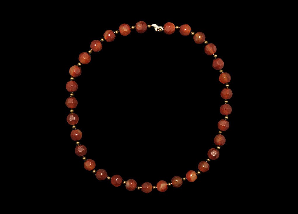 Western Asiatic Carnelian Bead Necklace: 19th-20th century AD. A string of polyhedral carnelian beads with spherical glass and metal spacers. 42 grams, 42cm (16 1/2"). Property of a London gentleman; acquired before 1980. [No Reserve]