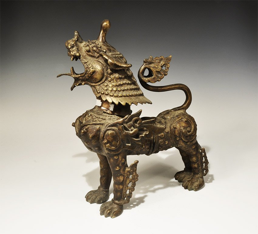 Chinese Nepalese Bronze Temple Lion: Nepal, 19th-early 20th century AD. Cast bronze figure of a temple lion with open mouth and lolling tongue, flame like fur on the shoulders and legs; tail ends in a floral motif. Guardian lion figure f