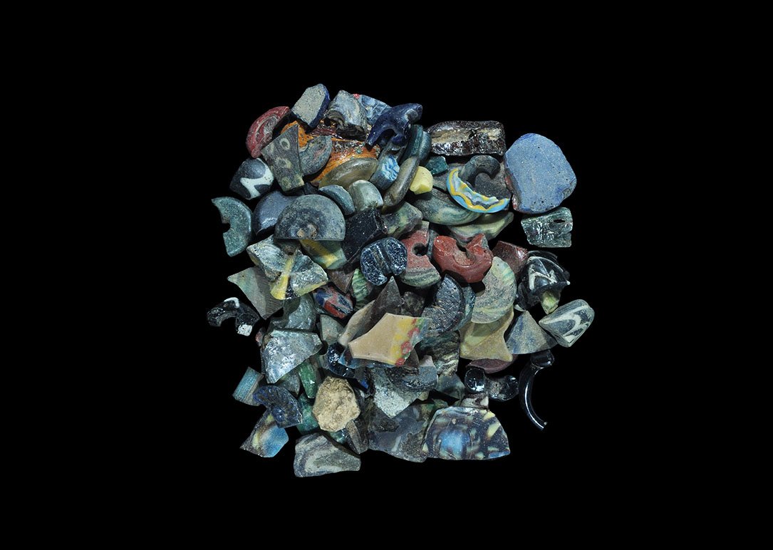 Egyptian Mixed Glass Item Group: Mainly Late Period, 664-332 BC. A mixed group of glass fragments including polychrome beads, pendants, vessels, tesserae and a finger ring. 105 grams total, 7-31mm (1/4 - 1 1/4"). Property of a lady;