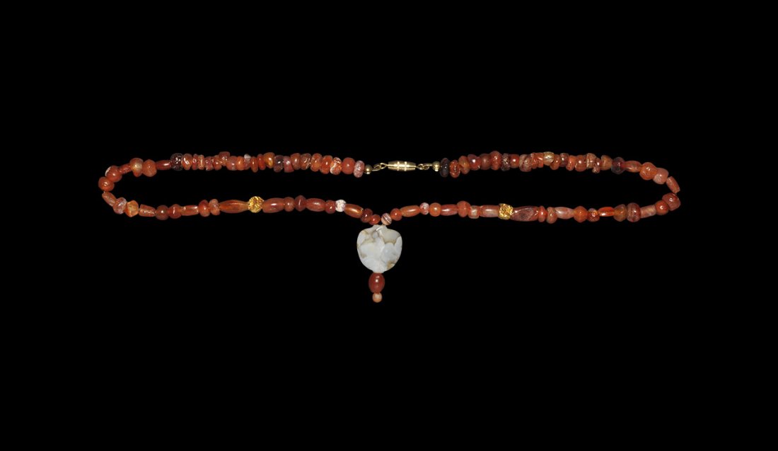 Roman Carnelian and Gold Bead Necklace: Mainly 1st-2nd century AD. A restrung necklace of tubular and irregular carnelian beads with two gold foil spacers and D-shaped banded agate dangle; modern clasp. 21 grams, 41cm (16"). English private